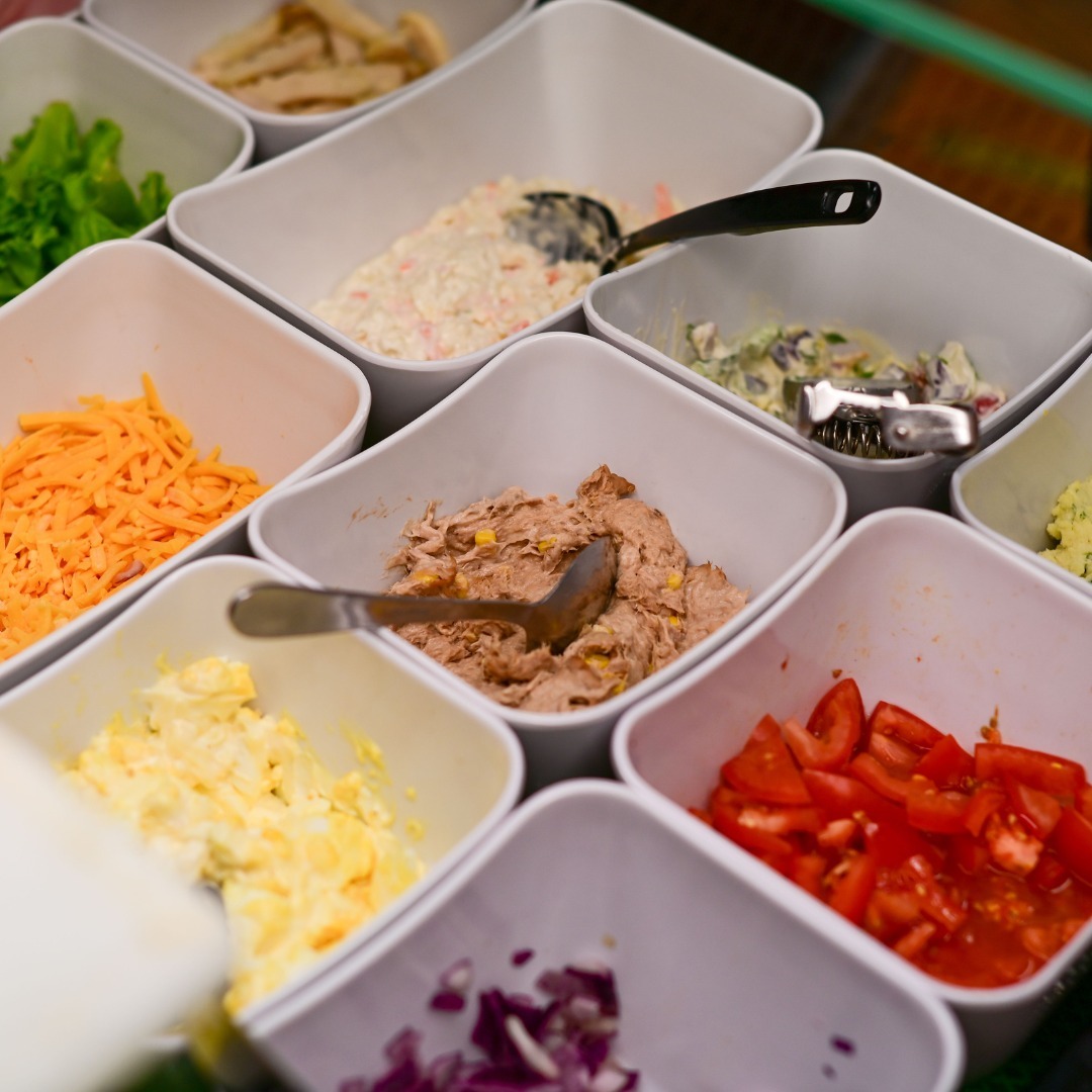 Salad bar trays of coleslaw, grated cheese, tuna mayonnaise, egg mayonnaise, chopped tomato, red onion and lettuce